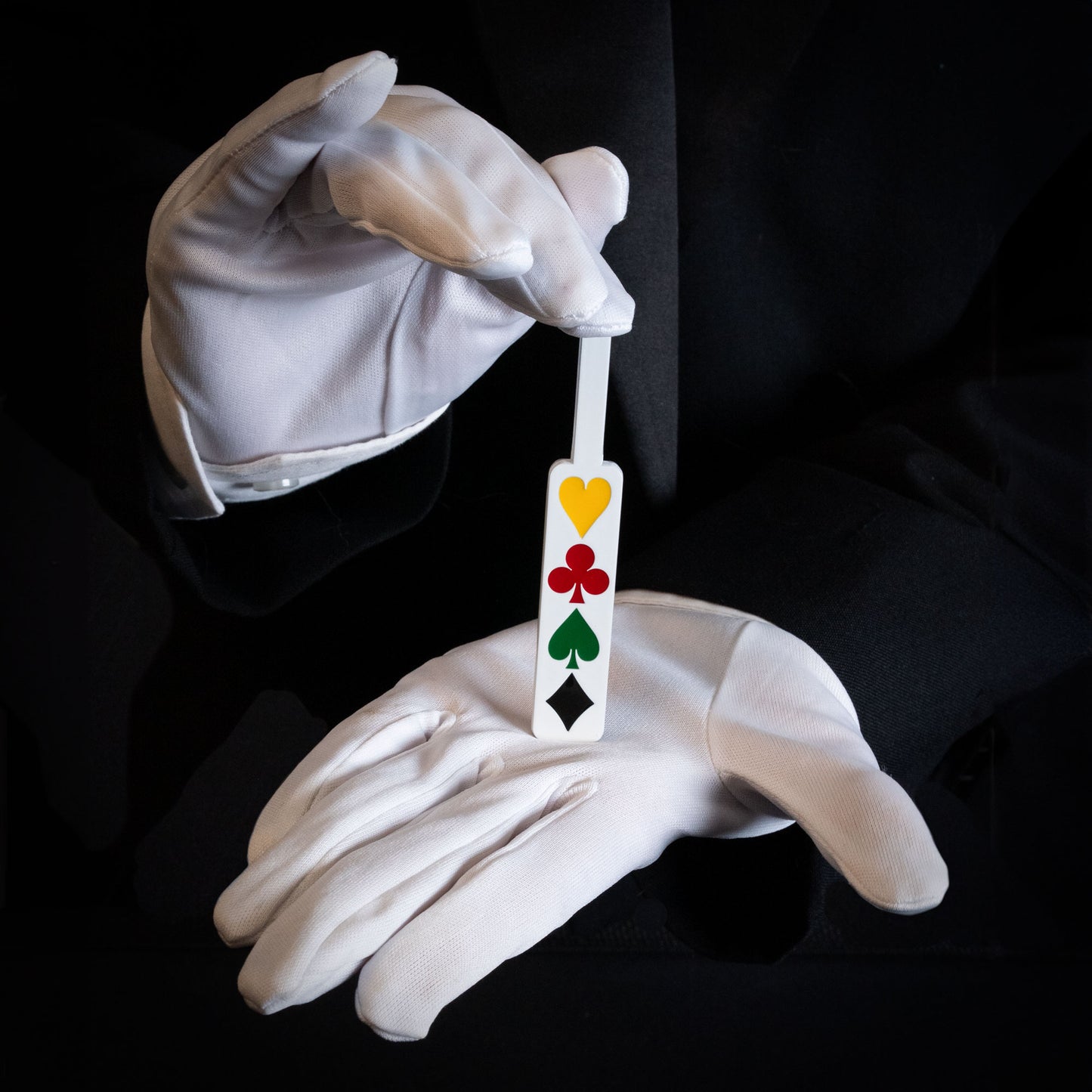 Close-up of the Deception Paddle, a metal magic trick tool painted white with vibrant enamel card pips for stunning illusions.