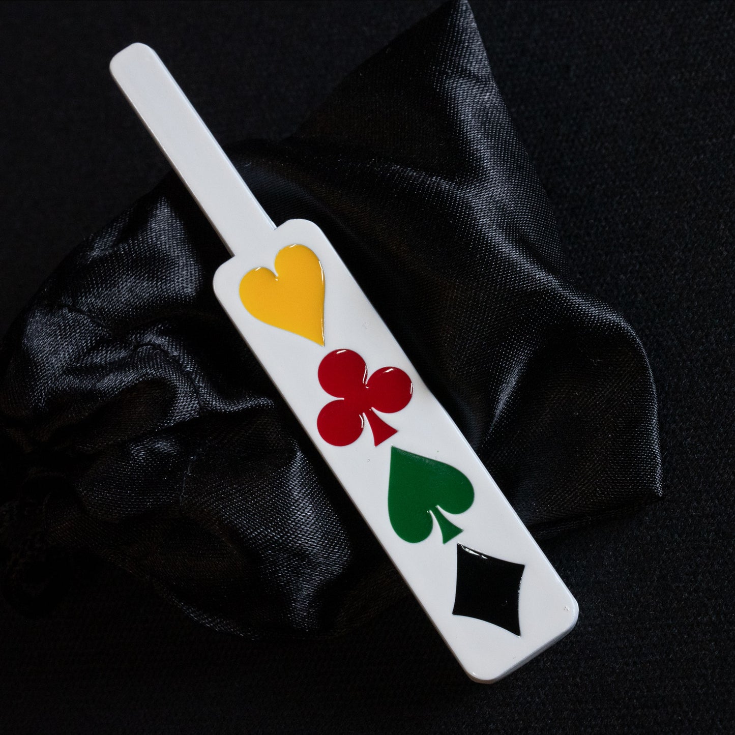 Detailed view of the Deception Paddle, a metal magic trick tool painted white with vibrant enamel card pips for stunning illusions.