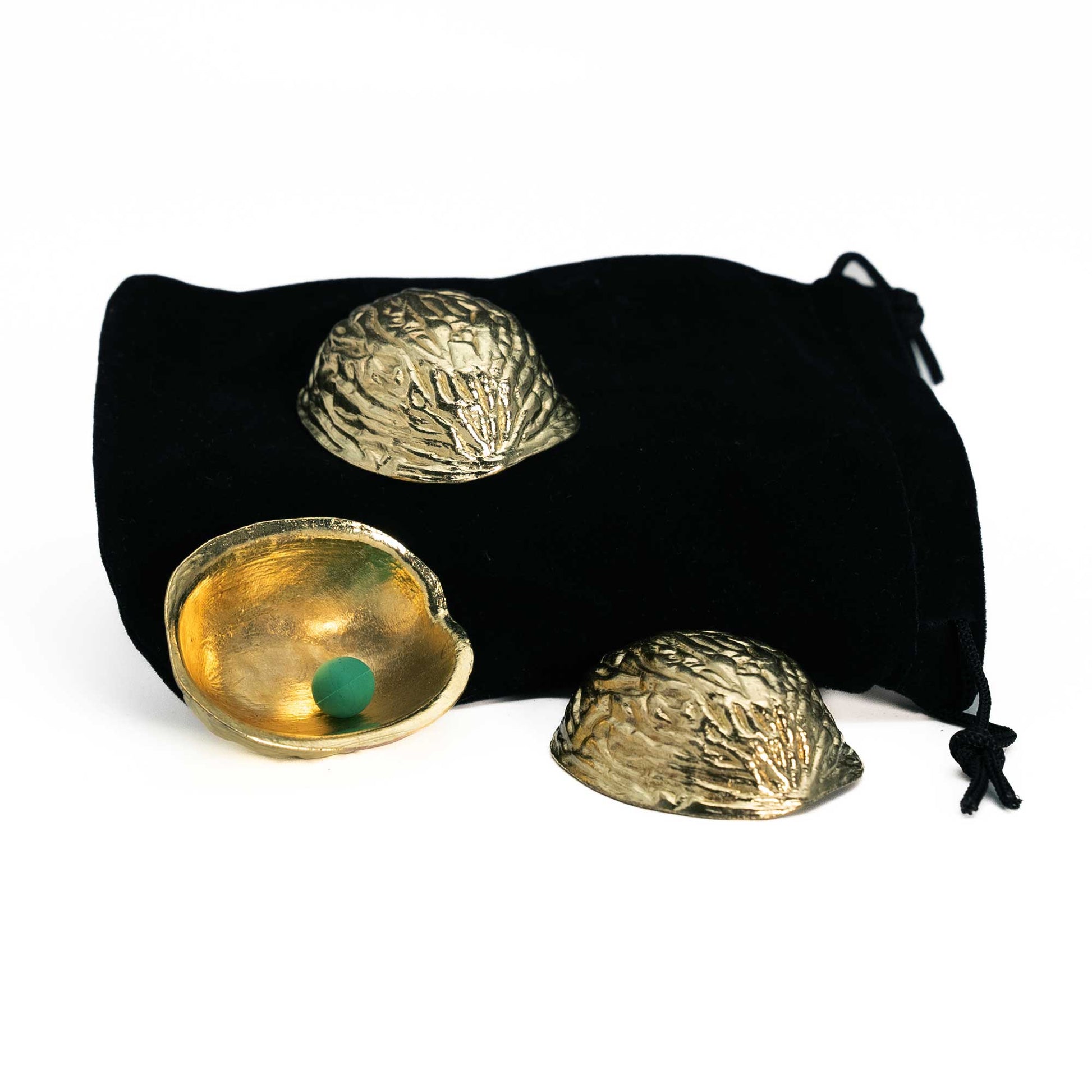 Gleaming gold-plated shells and a green pea sit on a velvet pouch, showcasing the classic Metal Golden 3 Shell Game set.