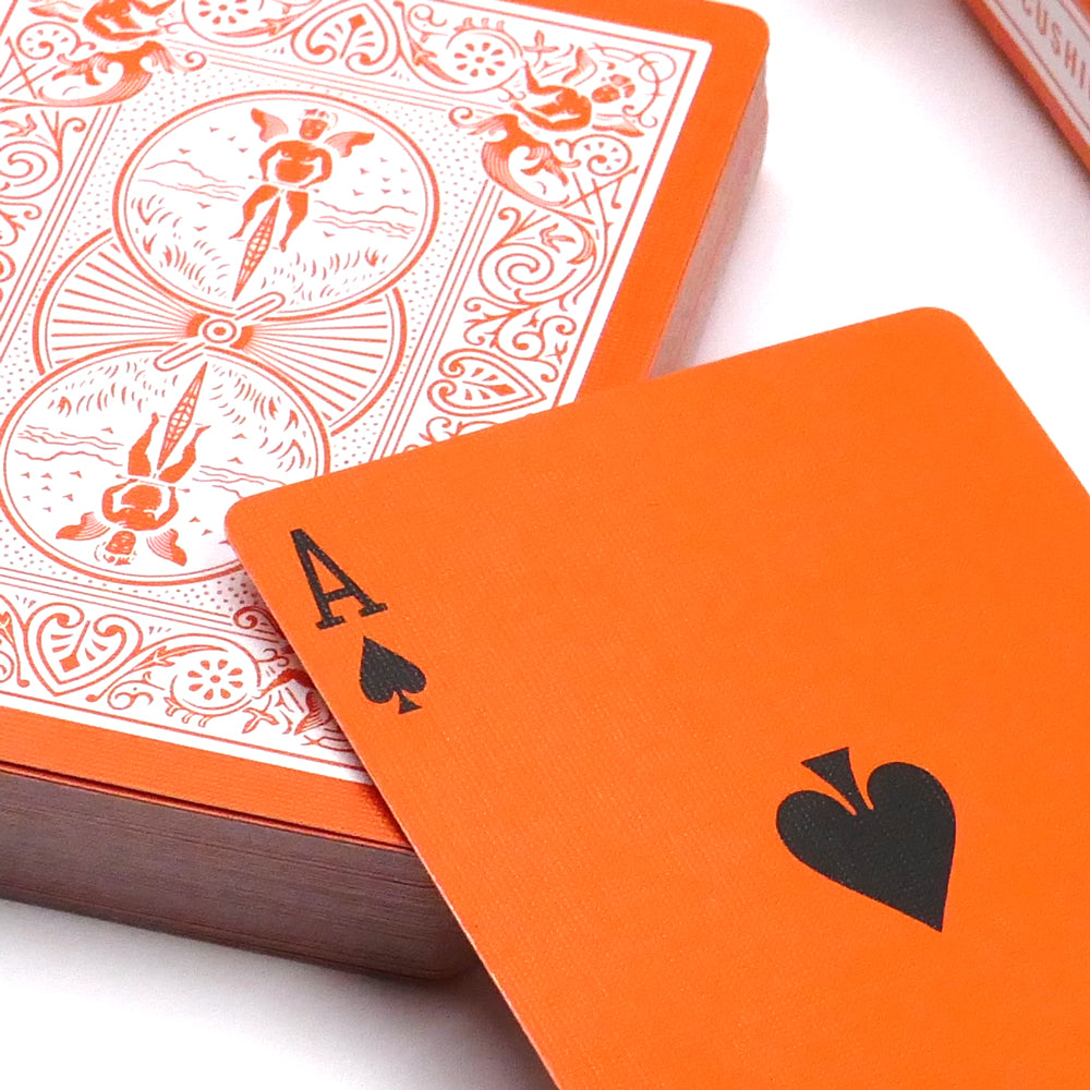 Vibrant orange Bicycle Back playing cards with a striking reversed white design on the back, perfect for card tricks.