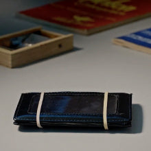 Compact Secret Mind Reading Device wallet in sleek black, secured with rubber bands, ready to reveal hidden thoughts.