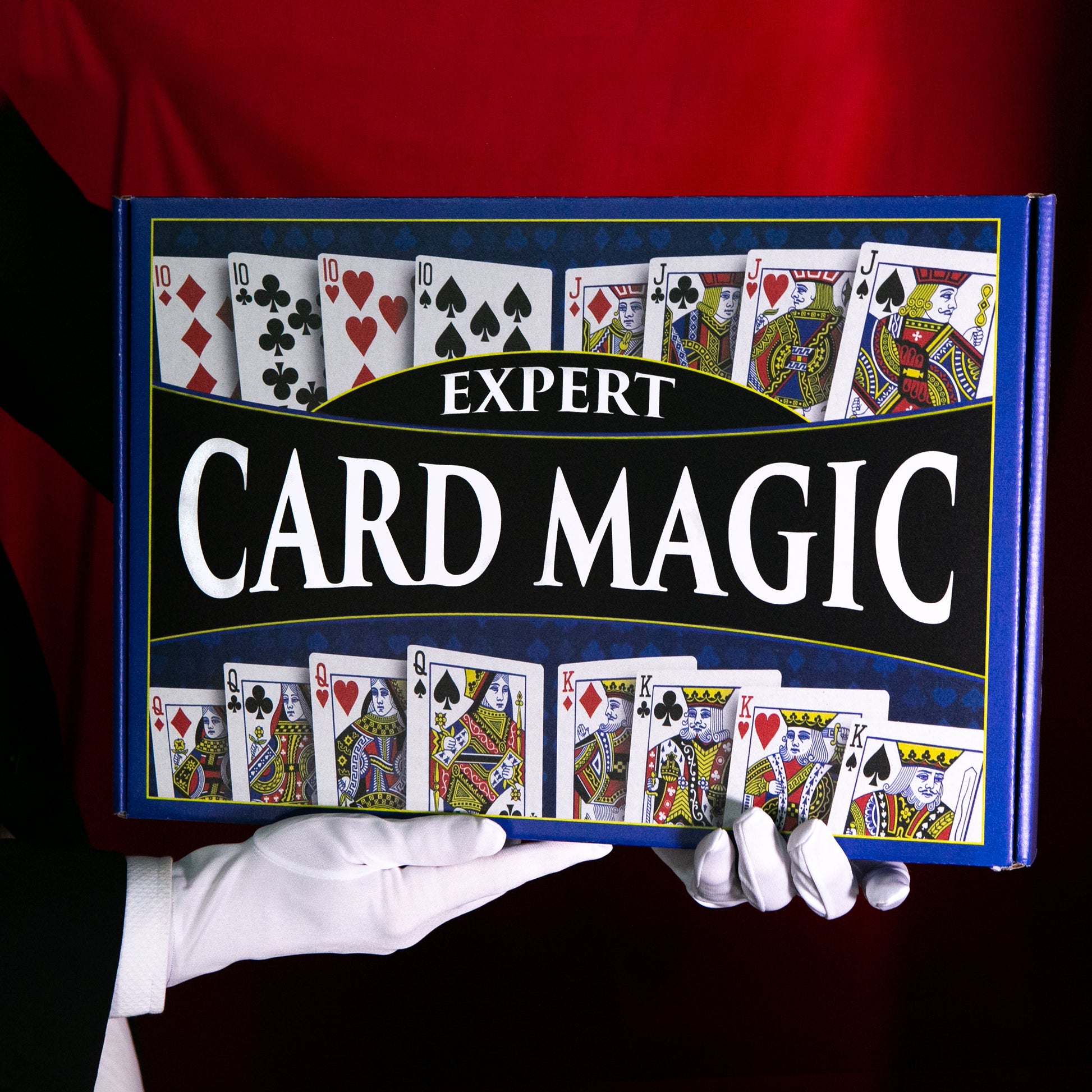 Detailed view of the Expert Card Magic Kit, showcasing a Blue Faded Bicycle Deck, a wood illusion card box, and magical accessories on a red close-up pad.