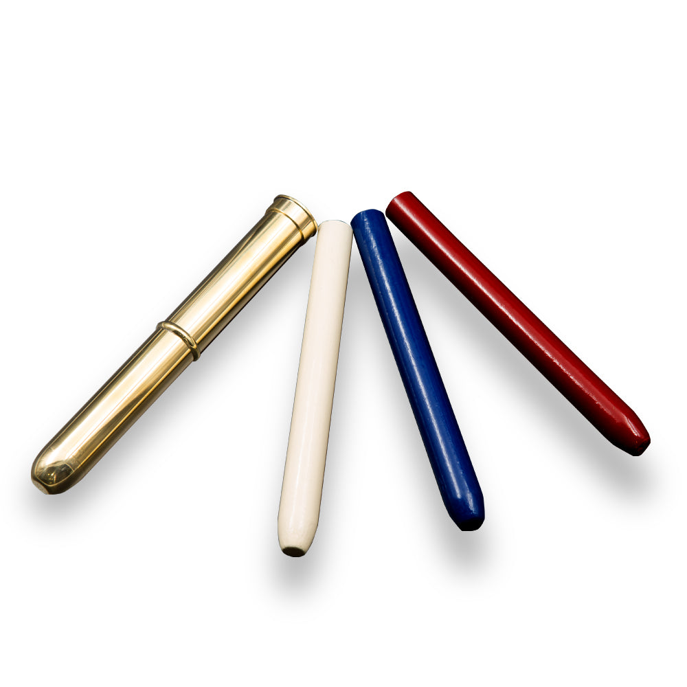 Four cylindrical objects—gold, white, blue, and red—are arranged fan-shaped on a white background, casting soft shadows. These form the Collector's Telepathic Tube, evoking the classic illusion or a magician’s treasured apparatus.